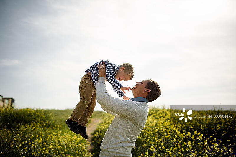 爸爸在野花田中举起儿子图片素材