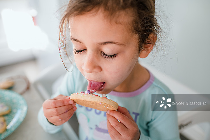 小女孩舔复活节彩蛋饼干上的糖霜图片素材