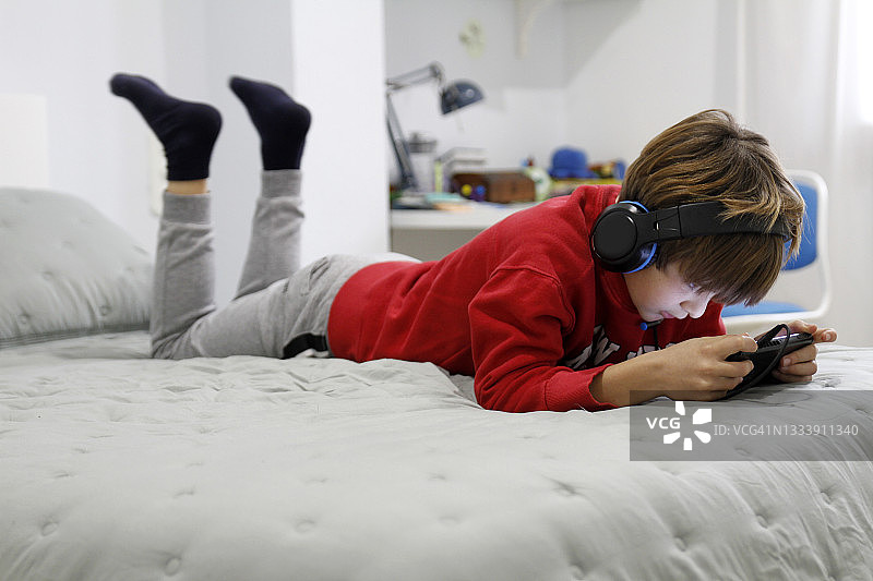 男孩在床上玩电子游戏图片素材