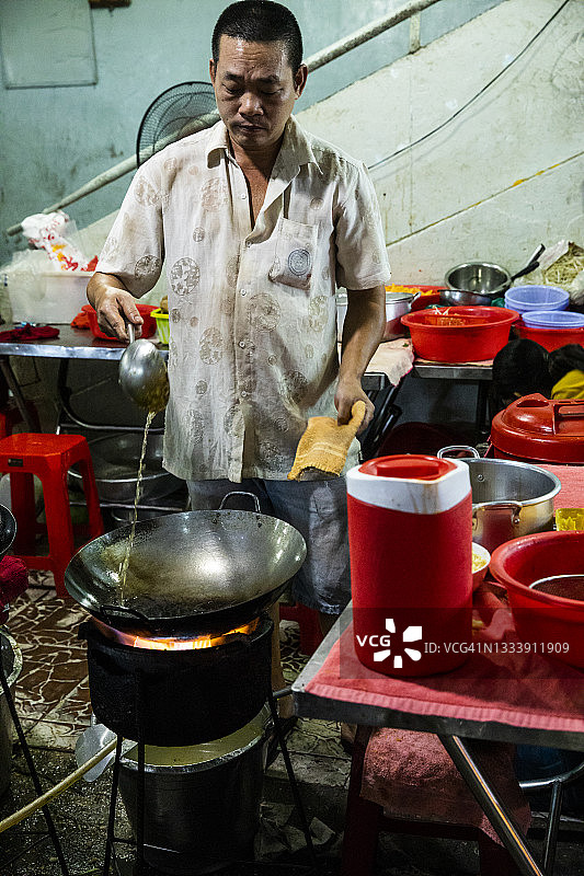 在西贡夜市烹饪：厨师用热油准备炒锅图片素材