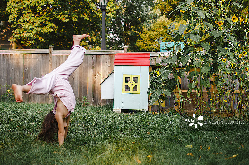 在后院彩色鸡舍旁空翻的小女孩图片素材