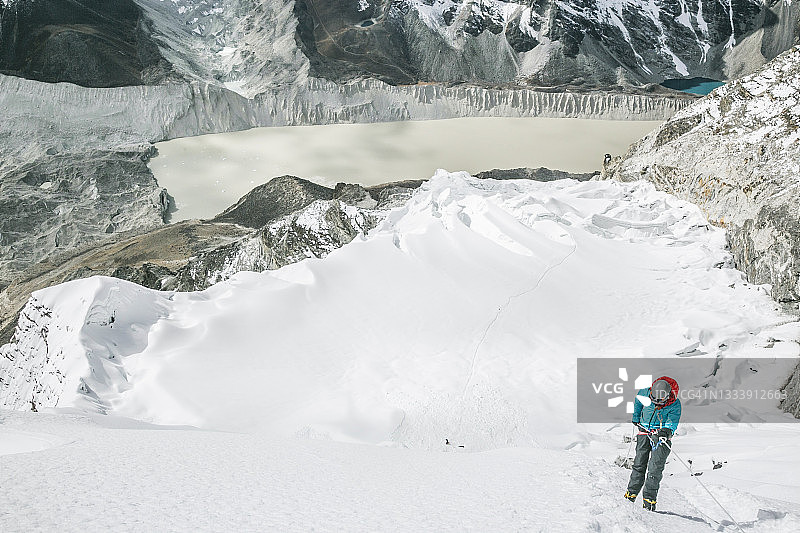 身穿蓝色夹克的女性登山者沿绳下降岛峰图片素材