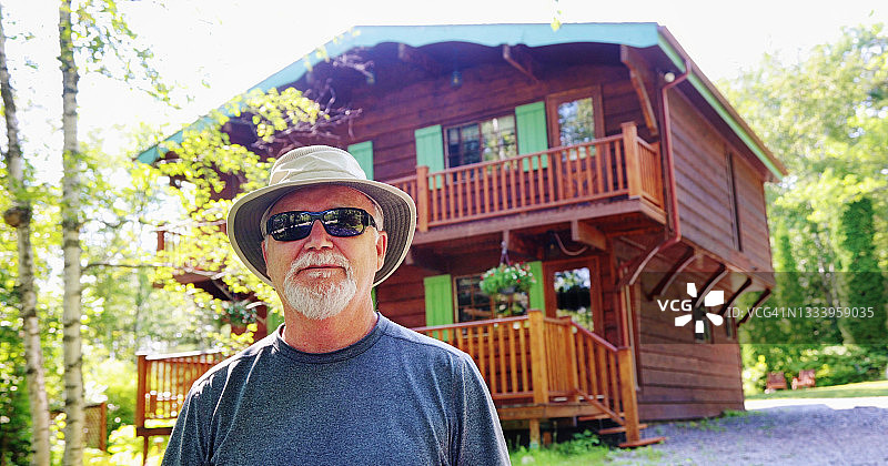 老年男人戴着帽子和太阳镜在他家门前的肖像图片素材