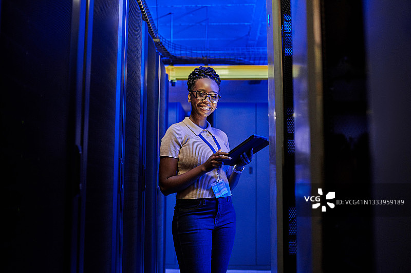 年轻女工程师在服务器机房工作时使用平板电脑图片素材
