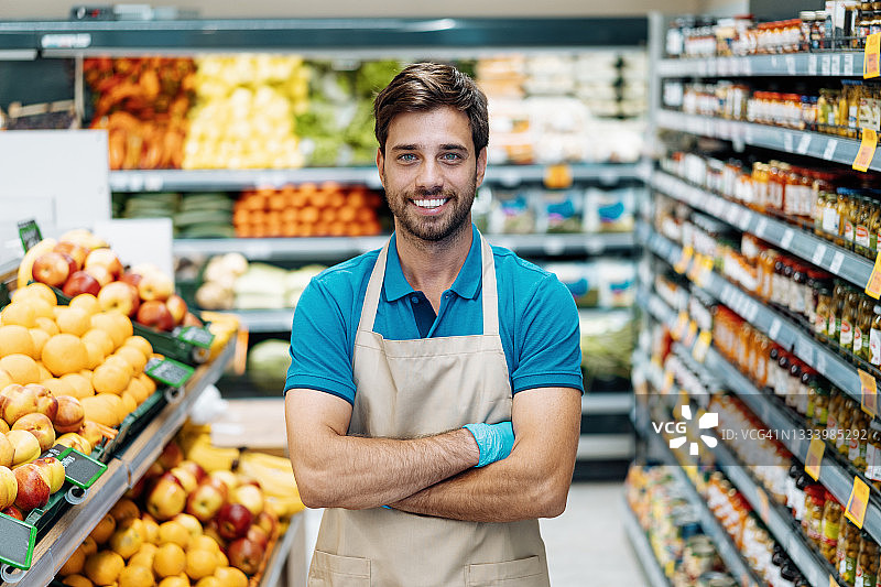 超市员工身穿蓝色POLO衫和围裙的肖像图片素材