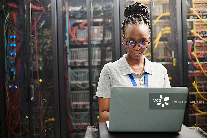 年轻女子在服务器机房使用笔记本电脑的照片图片素材