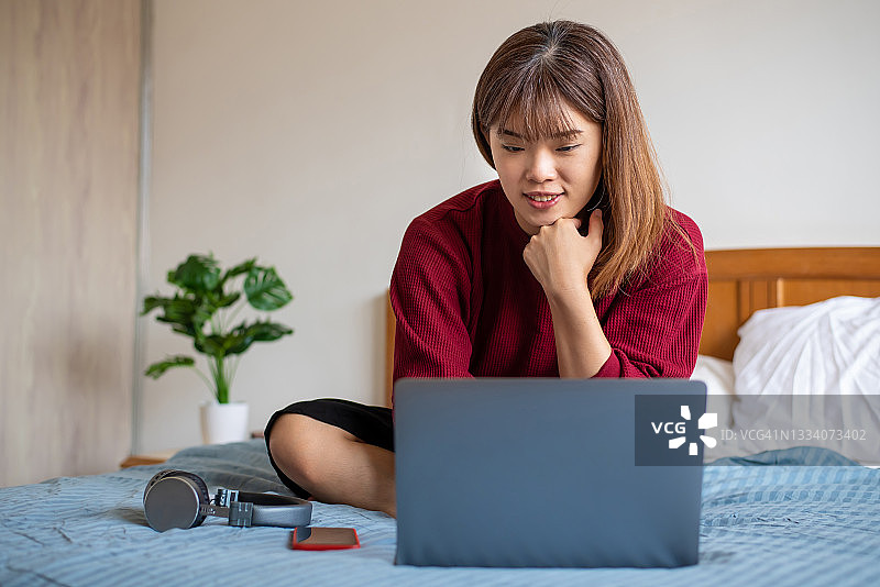 亚洲女人在床上使用笔记本电脑图片素材