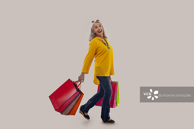 一位快乐地拿着彩色购物袋的老年妇女图片素材