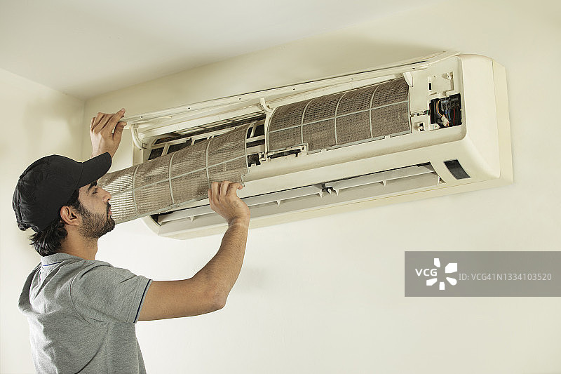 一位年轻的专业人士正在清洁空调图片素材