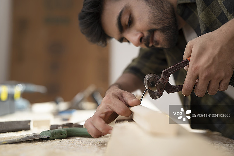 木匠用钳子拔钉子图片素材