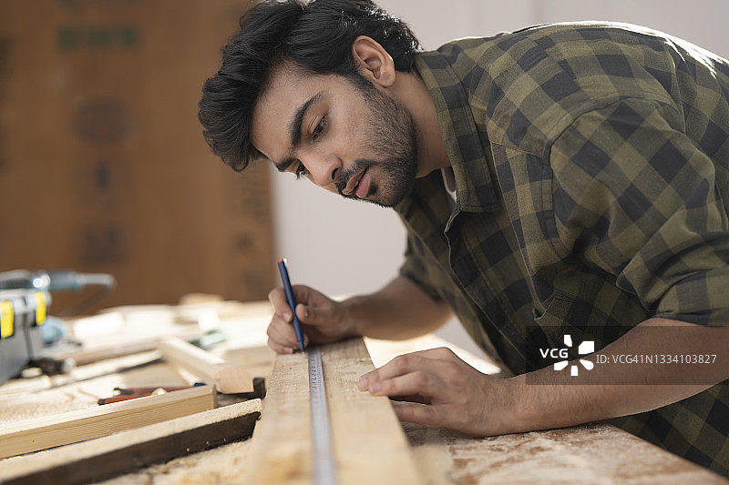 一位年轻木匠使用刻度尺标记木材图片素材