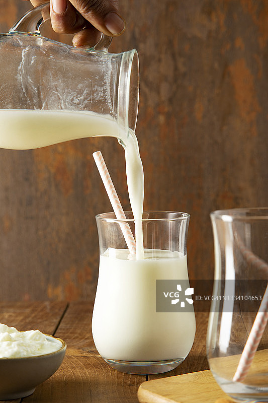 将酪乳从水罐倒入玻璃杯中图片素材