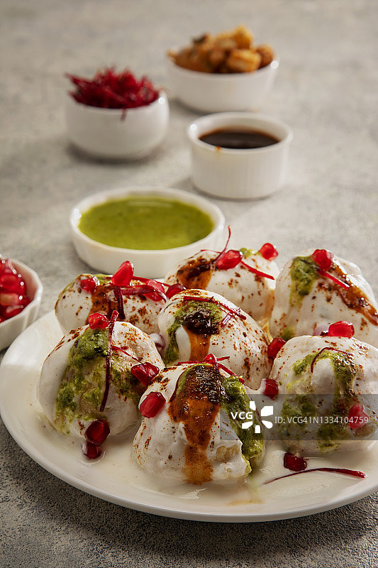 Dahi Vada或Dahi Bhalle是一道受欢迎的印度小吃，是油炸扁豆饺子，上面放着凝乳、甜酸辣酱和香料图片素材