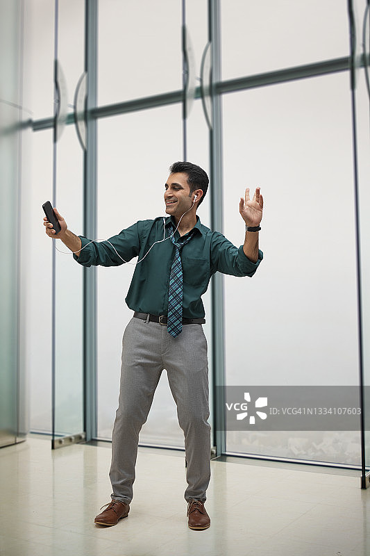 在办公室里快乐地听音乐跳舞的商务人士图片素材