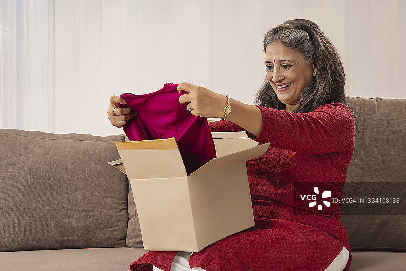 看着快递送来的新裙子的快乐老妇人图片素材