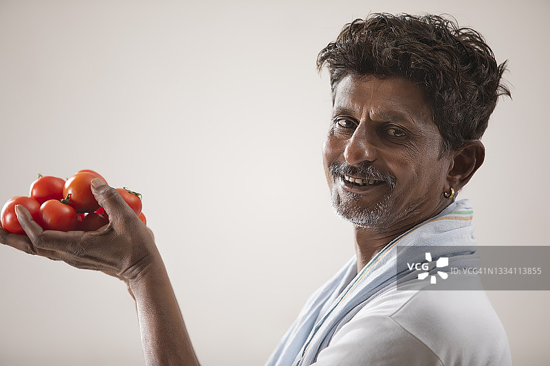 拿着樱桃番茄的印度农民图片素材