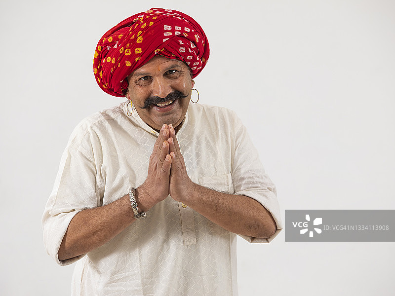 一位头戴头巾的快乐村民双手合十致意图片素材