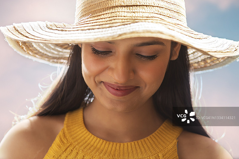 戴着夏日帽子向下看并微笑的快乐女人图片素材