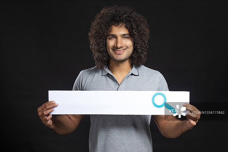 快乐的卷发年轻人拿着搜索栏图片素材