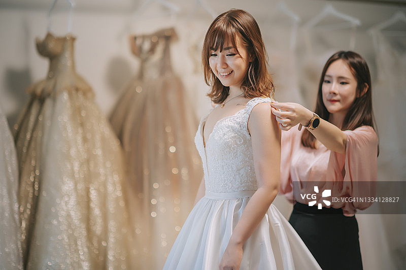 亚洲华人婚纱店主为顾客测量肩宽，定制婚纱图片素材