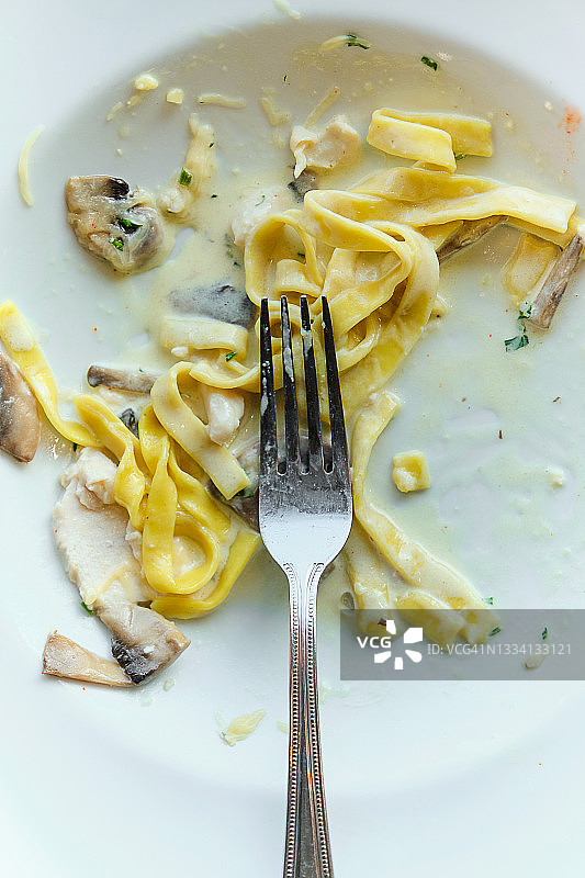 盛有蘑菇的意大利面白色盘子。奶油酱意大利面残羹图片素材