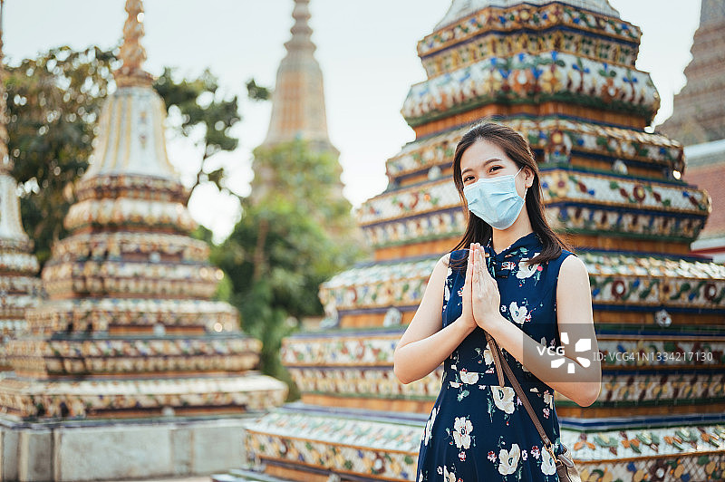 新常态生活方式：戴口罩的亚洲游客在曼谷郑王庙祈祷图片素材