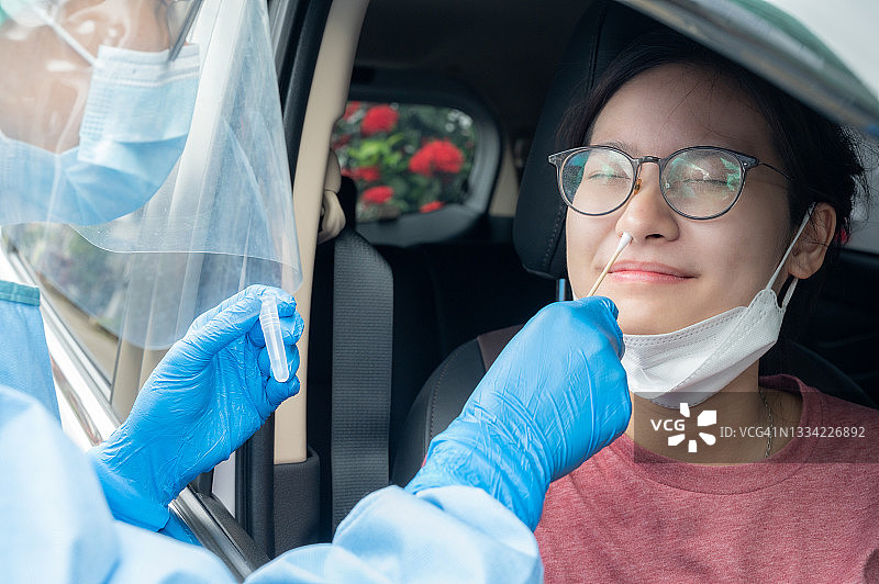 医护人员在新冠病毒检测站为亚洲女性进行鼻拭子采样，检测新冠病毒感染图片素材