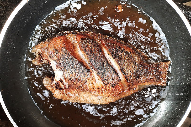 在煎锅中煎罗非鱼图片素材