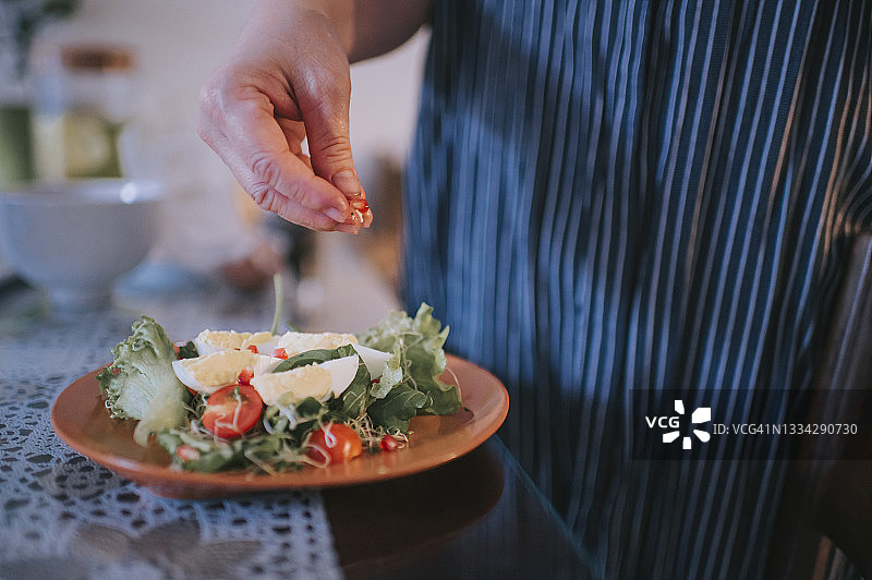 近距离拍摄：亚洲中年女性准备健康早餐沙拉图片素材