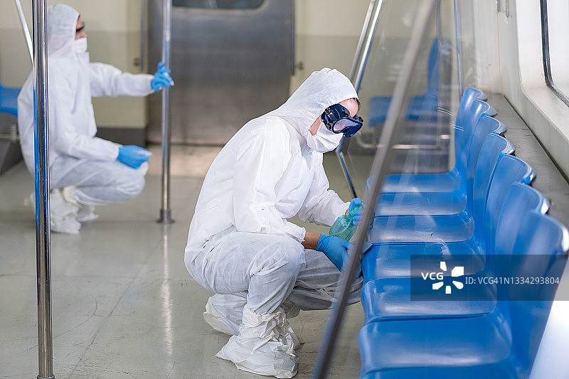 两名工作人员身穿全套PPE防护服清洁地铁或轻轨的不同部分图片素材