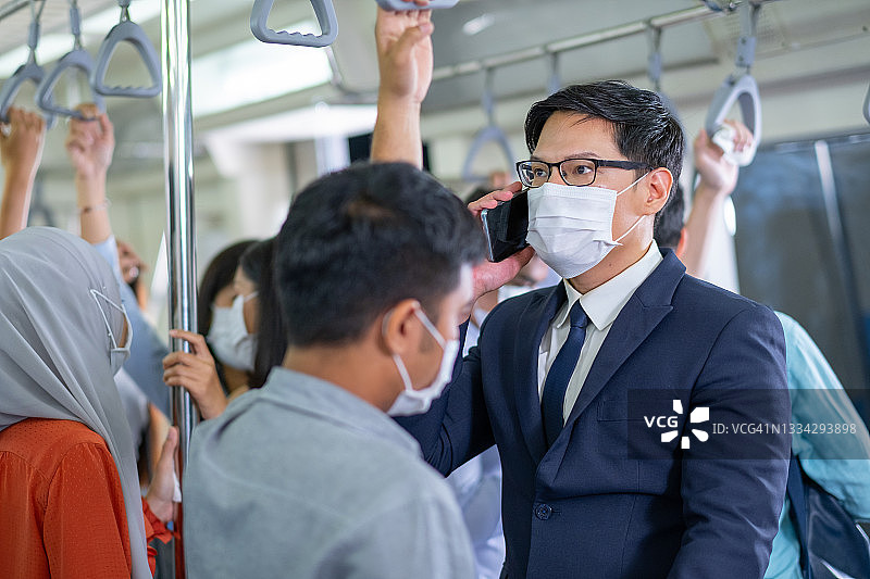 疫情期间佩戴口罩的亚洲商务人士乘坐地铁或轻轨上下班图片素材