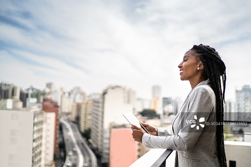 年轻女商人在屋顶沉思并使用平板电脑图片素材