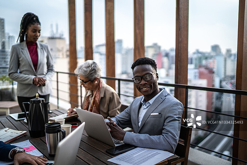 在屋顶与同事一起工作的快乐商人肖像图片素材
