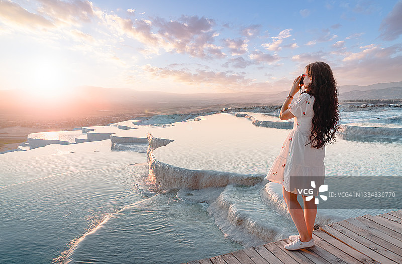 旅行者在棉花堡日落时拍摄石灰华水池图片素材