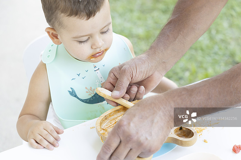 可爱的小男孩在爷爷的帮助下吃饭图片素材