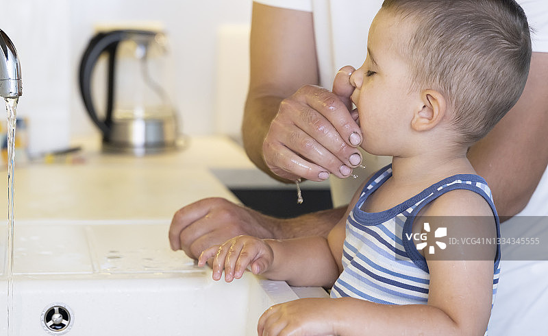 父亲帮助年幼的儿子刷手和牙齿图片素材