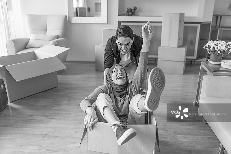 微笑的年轻人和戴着头巾的穆斯林女朋友刚进入新家，玩得很开心图片素材