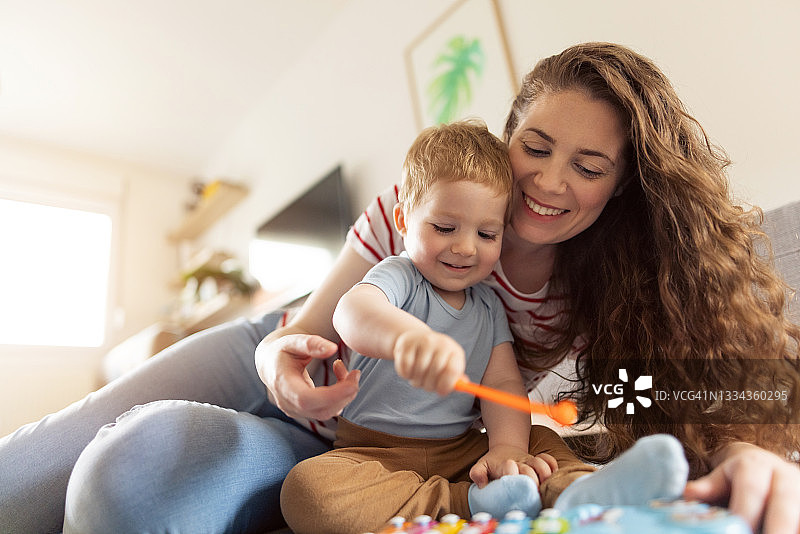 快乐的母亲和她的男婴一起演奏金属琴图片素材