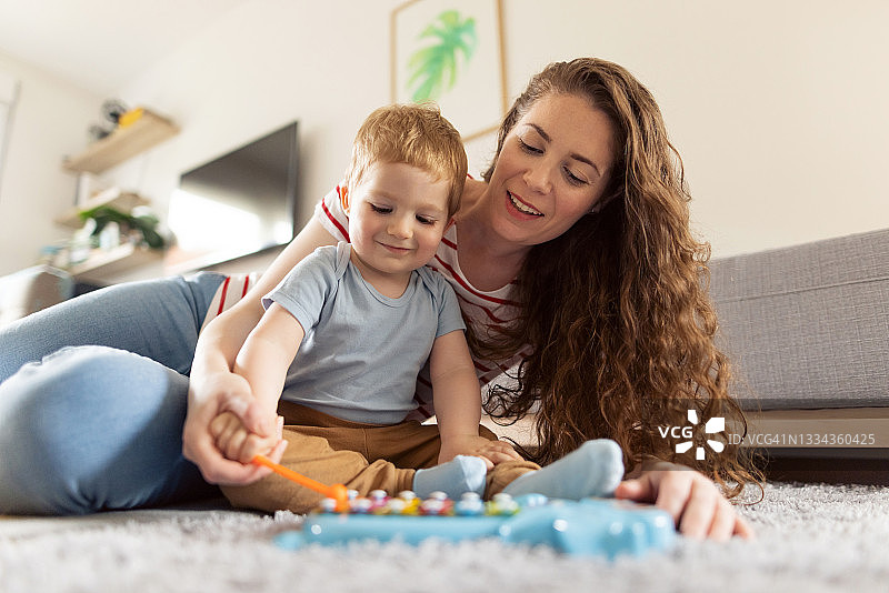 快乐的母亲和她的男婴一起玩金属琴图片素材