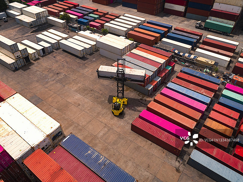 航拍：叉车在配送仓库将集装箱装载到卡车上，准备运往集装箱船，用于商业物流、进出口运输或货运图片素材