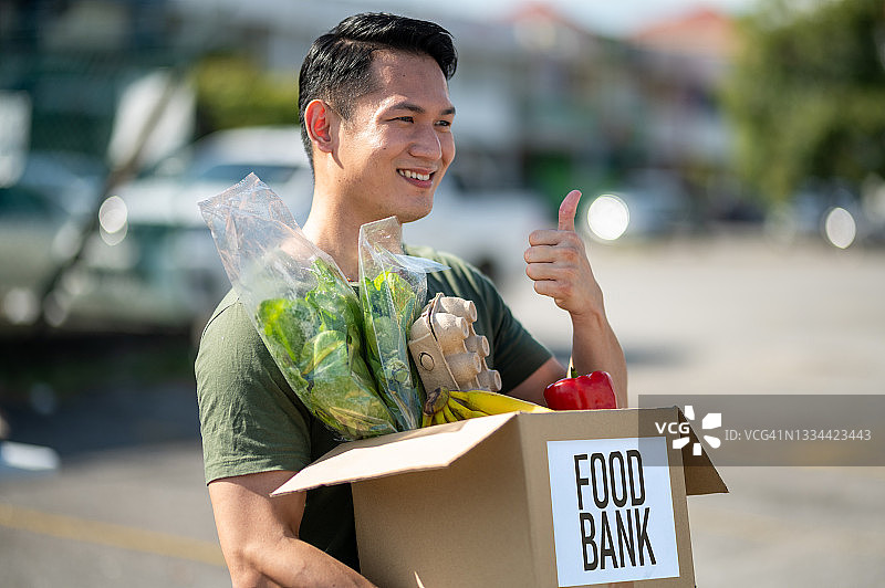 快乐的亚洲男人志愿者拿着捐赠箱图片素材