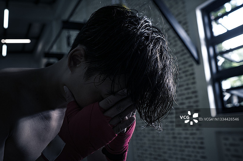 亚洲青年拳击手在拳击比赛失败后感到消极和悲伤，并向前看图片素材