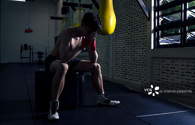 比赛失败后情绪失落的亚洲年轻女拳击手图片素材