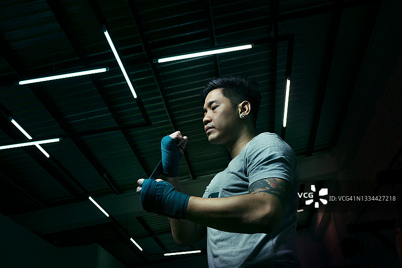 准备拳击绷带，戴拳击手套开始训练的亚洲运动型男子图片素材