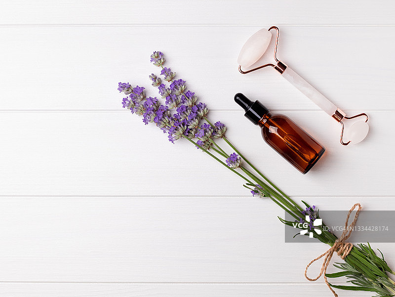 白色木质背景上的薰衣草、化妆品瓶和微针滚轮（带文案空间）图片素材