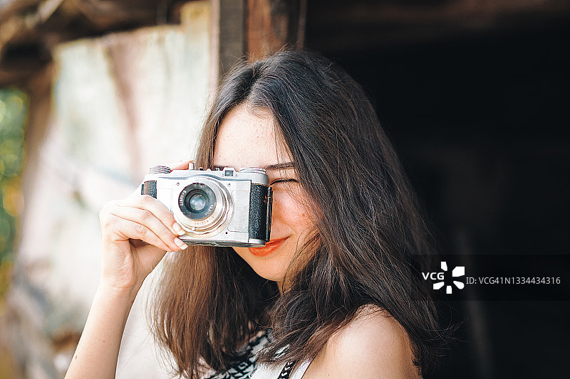 少女摄影师在户外使用老式模拟胶片相机图片素材