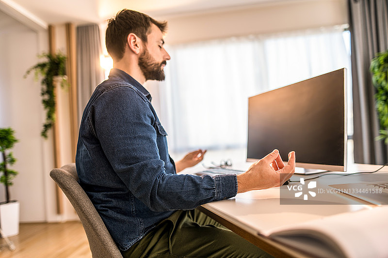 在家中办公室工作休息时冥想的年轻男人图片素材