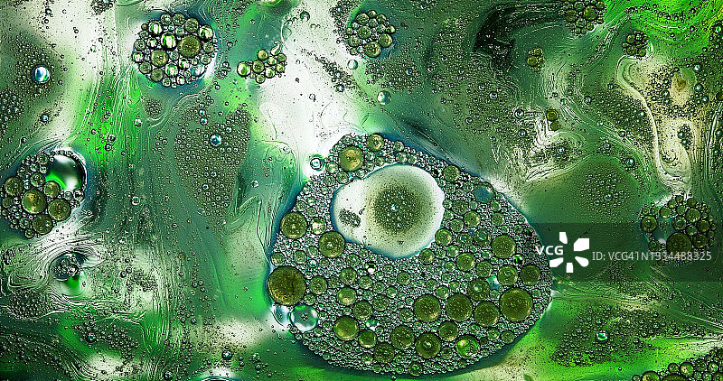 绿色背景水面上漂浮的液体斑点和气泡图片素材