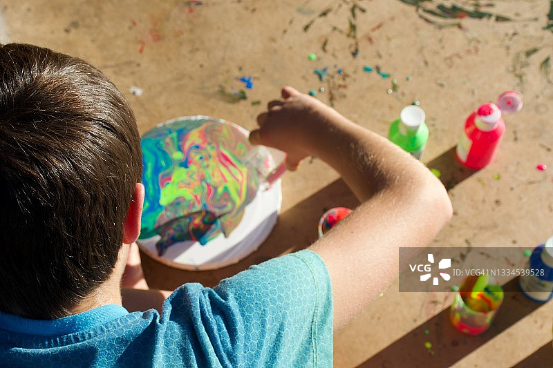 男孩在圆形画布上制作大理石效果画图片素材