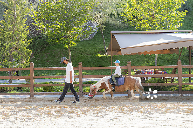 骑在马上的孩子和马夫图片素材